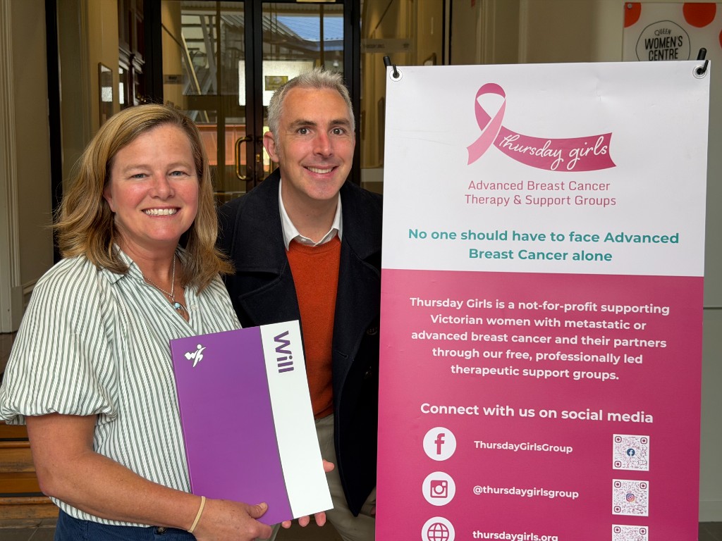 Will Hero co-founder John Ryan with Thursday Girls Vice President Jodi Webb, holding a Will Hero Will, beside a Thursday Girls banner.